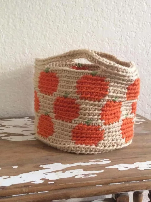 small crochet textured basket with tapestry pumpkins on a cream background