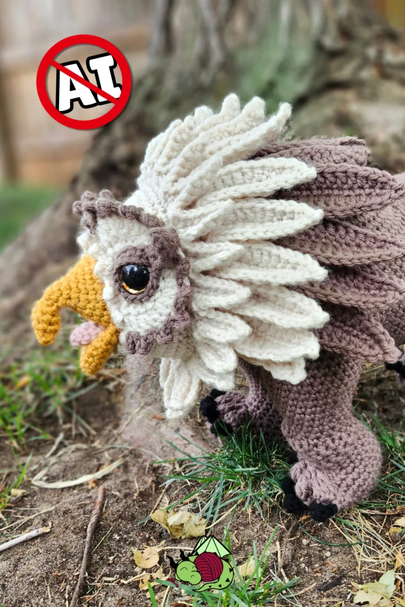 A brown crochet owl bear amigurumi with tan feathers and his beak open, a dungeons and dragons creature in the woods.
