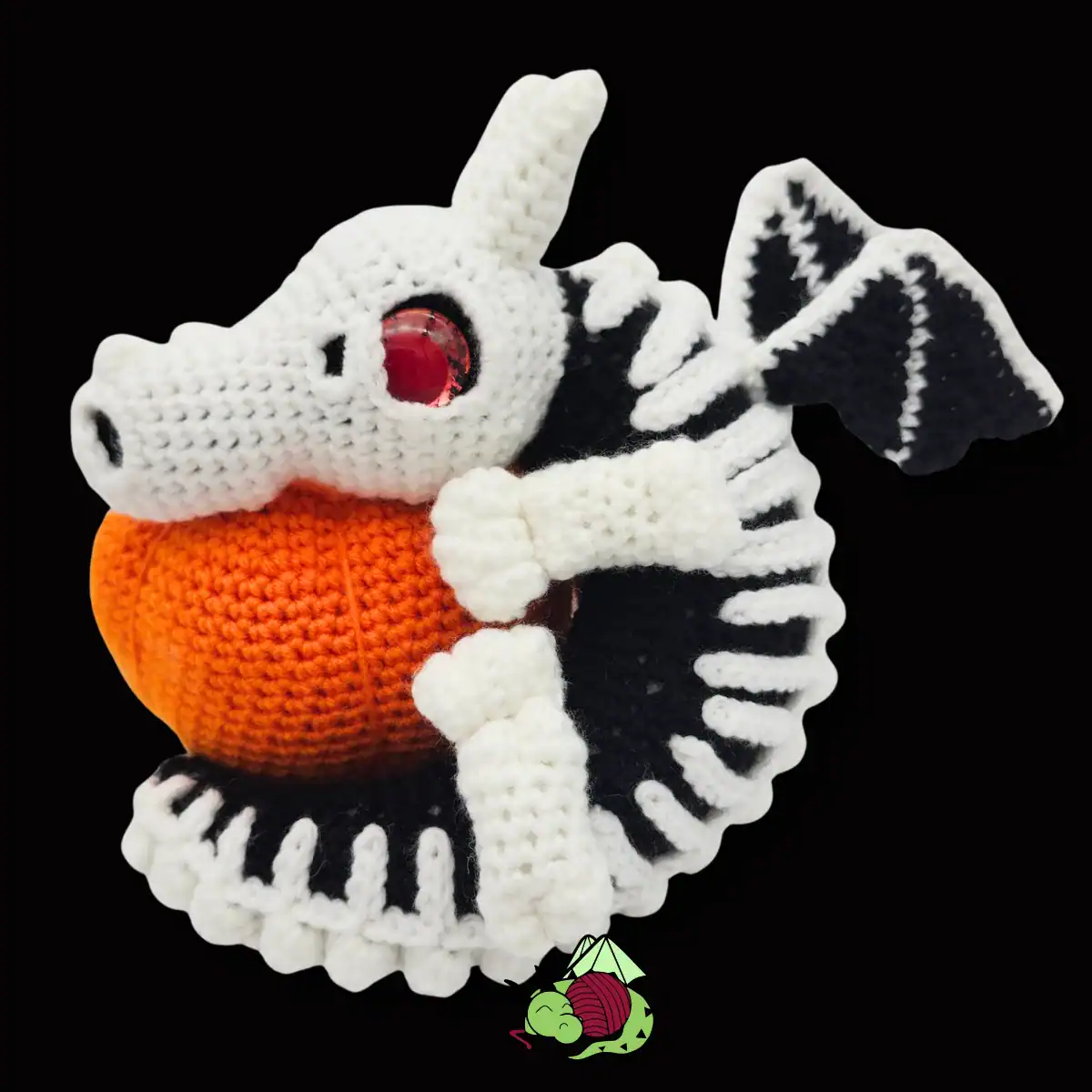 a small crochet skeleton dragon wrapped around a crochet pumpkin.